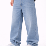 Men wearing light blue oversized fit denim jeans with relaxed streetwear style and casual white-blue sneakers.