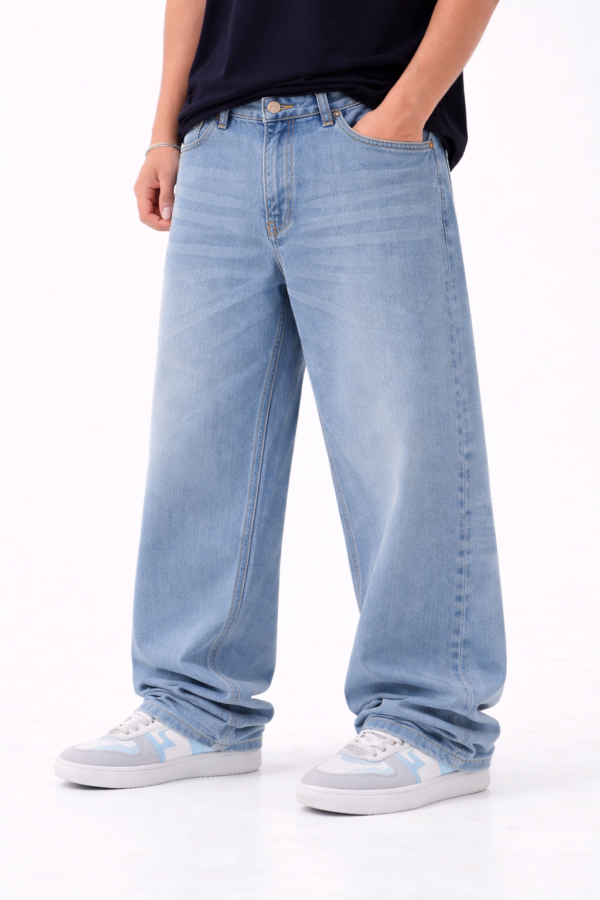 Men wearing light blue oversized fit denim jeans with relaxed streetwear style and casual white-blue sneakers.