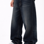 Men wearing dark blue oversized fit denim jeans with relaxed streetwear style and casual sneakers.