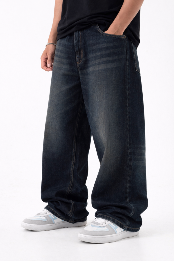 Men wearing dark blue oversized fit denim jeans with relaxed streetwear style and casual sneakers.