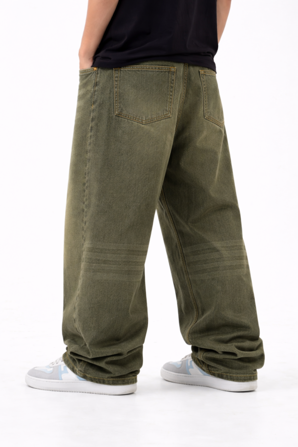 Back view of men’s olive green oversized fit denim jeans with relaxed streetwear style and casual sneakers.